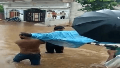 Family carries pregnant woman on cot, wades through knee-deep water