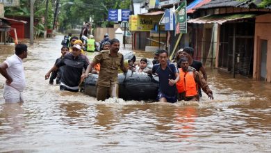 Rescuers evacuate people from a flooded area to a safer place in Aluva